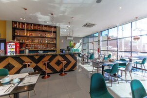 Un restaurante moderno con barra, asientos y ventanas amplias.