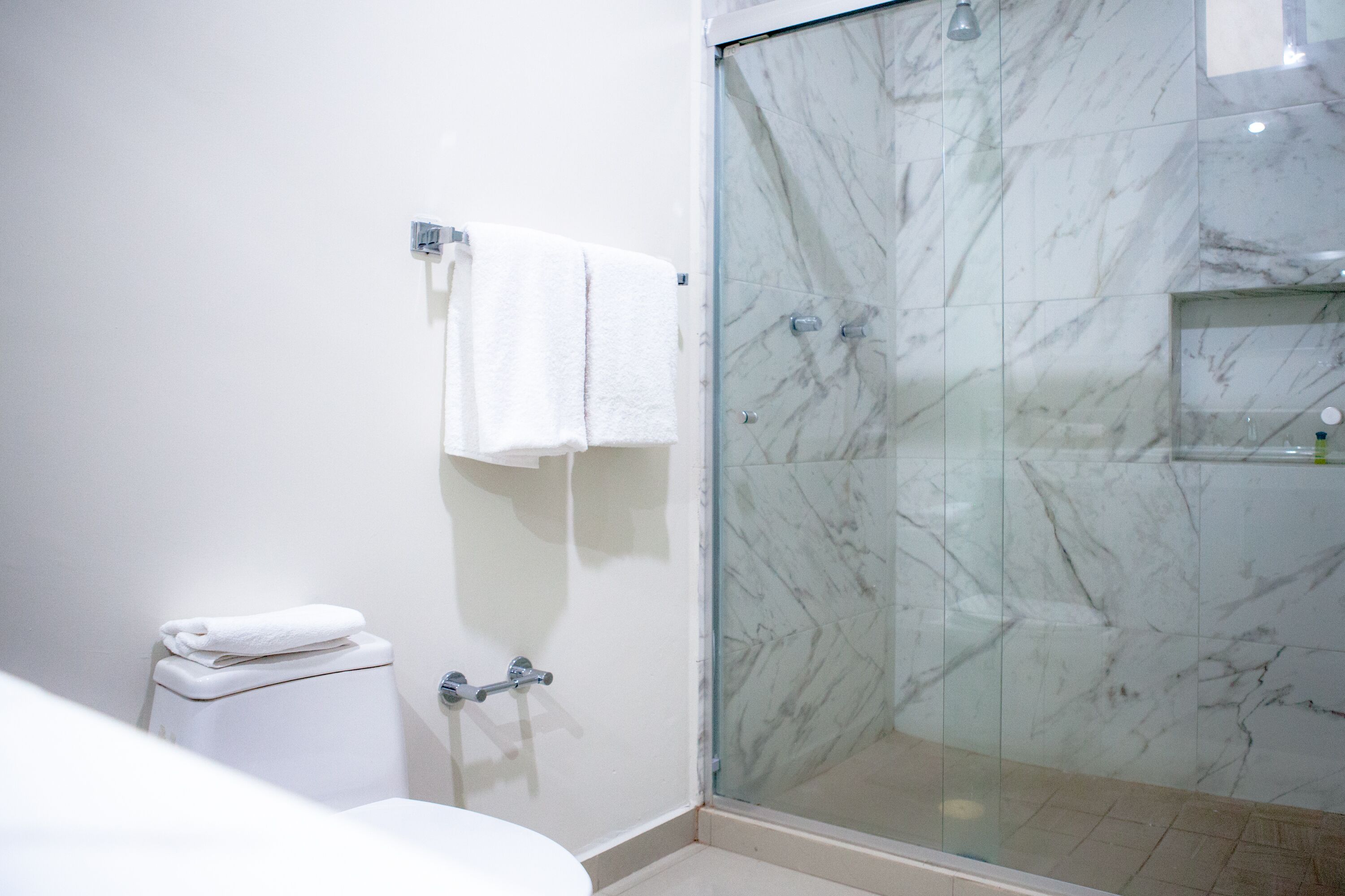 Un baño con cabina de ducha de vidrio, inodoro y lavabo.