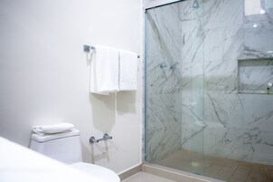 Un baño con cabina de ducha de vidrio, inodoro y lavabo.