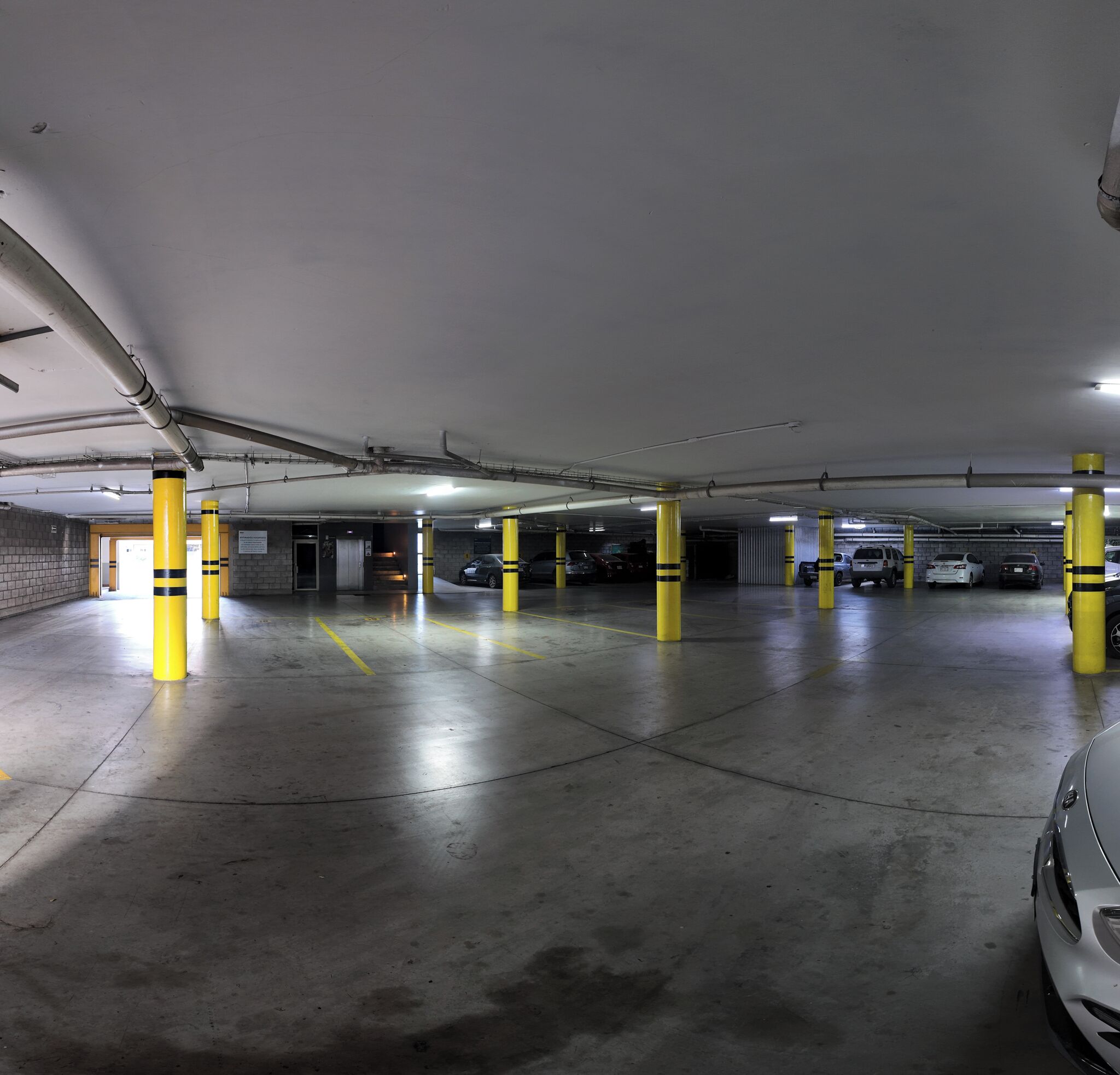 Un estacionamiento subterráneo de varios niveles con pilares amarillos y pisos de concreto.