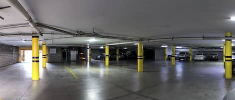 Un estacionamiento subterráneo de varios niveles con pilares amarillos y pisos de concreto.