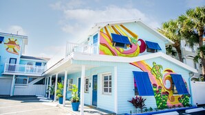 A two-story building with a colorful mural, a balcony, and a covered porch area. - Sunburst Inn (Indian Shores)