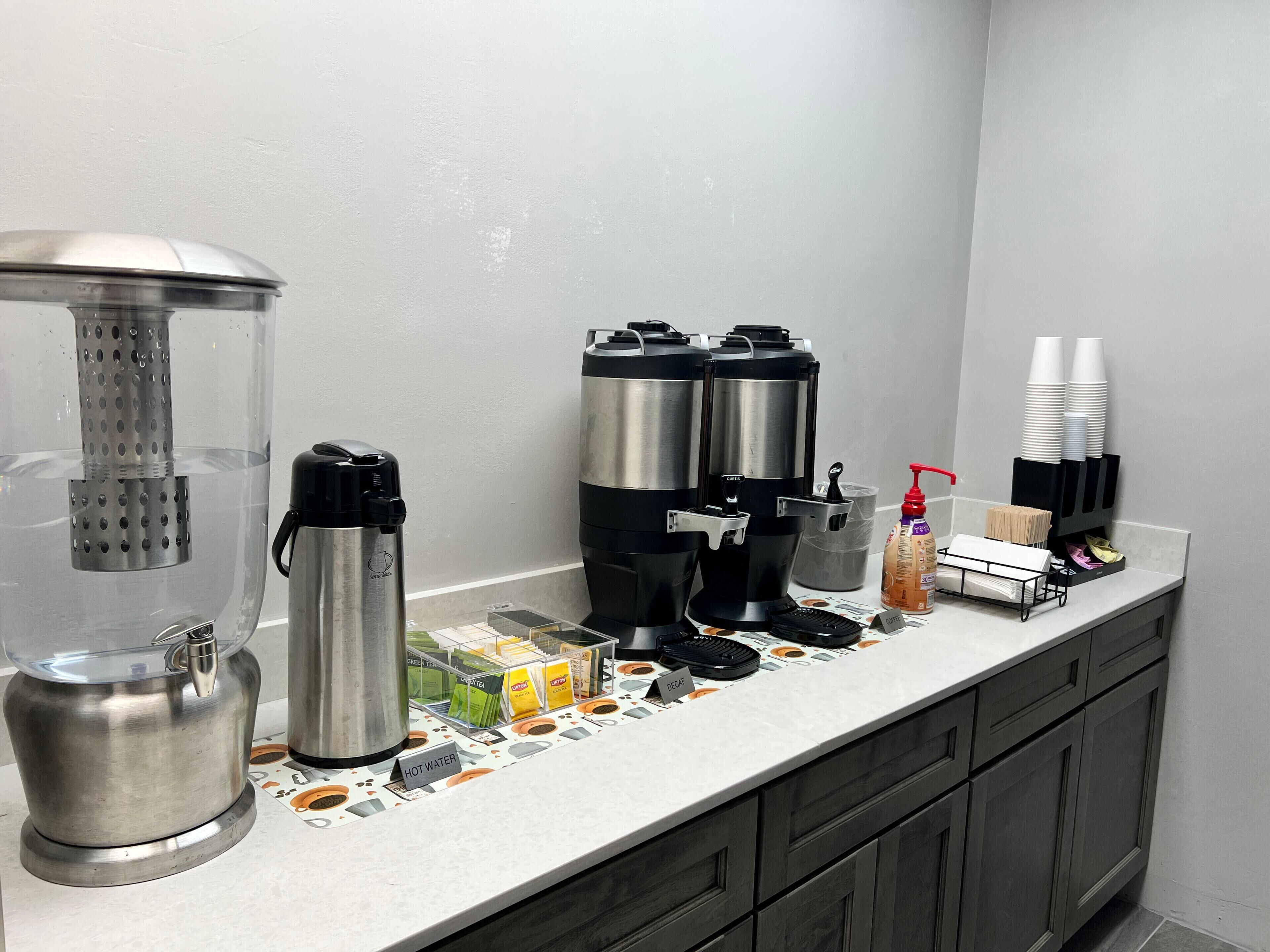 A coffee station with multiple coffee dispensers, a water dispenser, and a coffee mug.