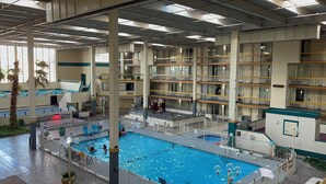 A multi-level indoor swimming pool with a central pool area surrounded by balconies and a covered walkway.