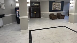 A lobby with a vending machine, two armchairs, a door, and a wall-mounted artwork. - The Lodge Hotel and Banquets (Bridgeton)