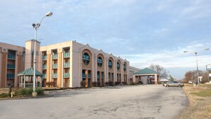 A hotel with multiple balconies, a covered parking area, and a clear sky.