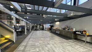 A spacious indoor area with a long counter, seating, and a staircase. - The Lodge Hotel and Banquets (Bridgeton)