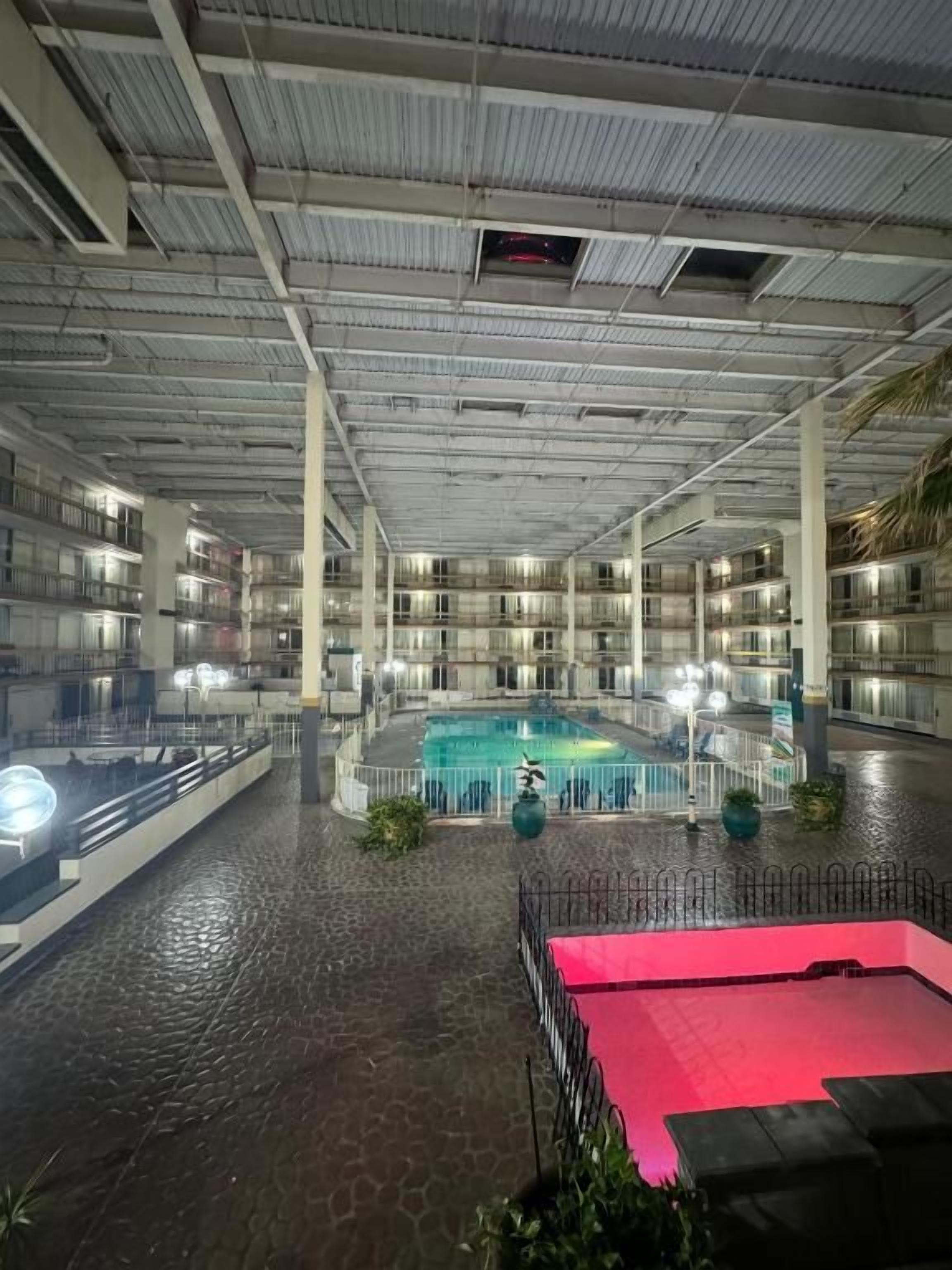 Una piscina interna con pavimento piastrellato, circondata da balconi e ringhiere.