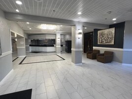 A spacious lobby with a reception desk, seating area, and a large artwork on the wall.