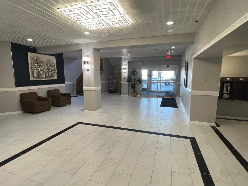 A spacious lobby with a tiled floor, a reception desk, and a seating area with chairs.