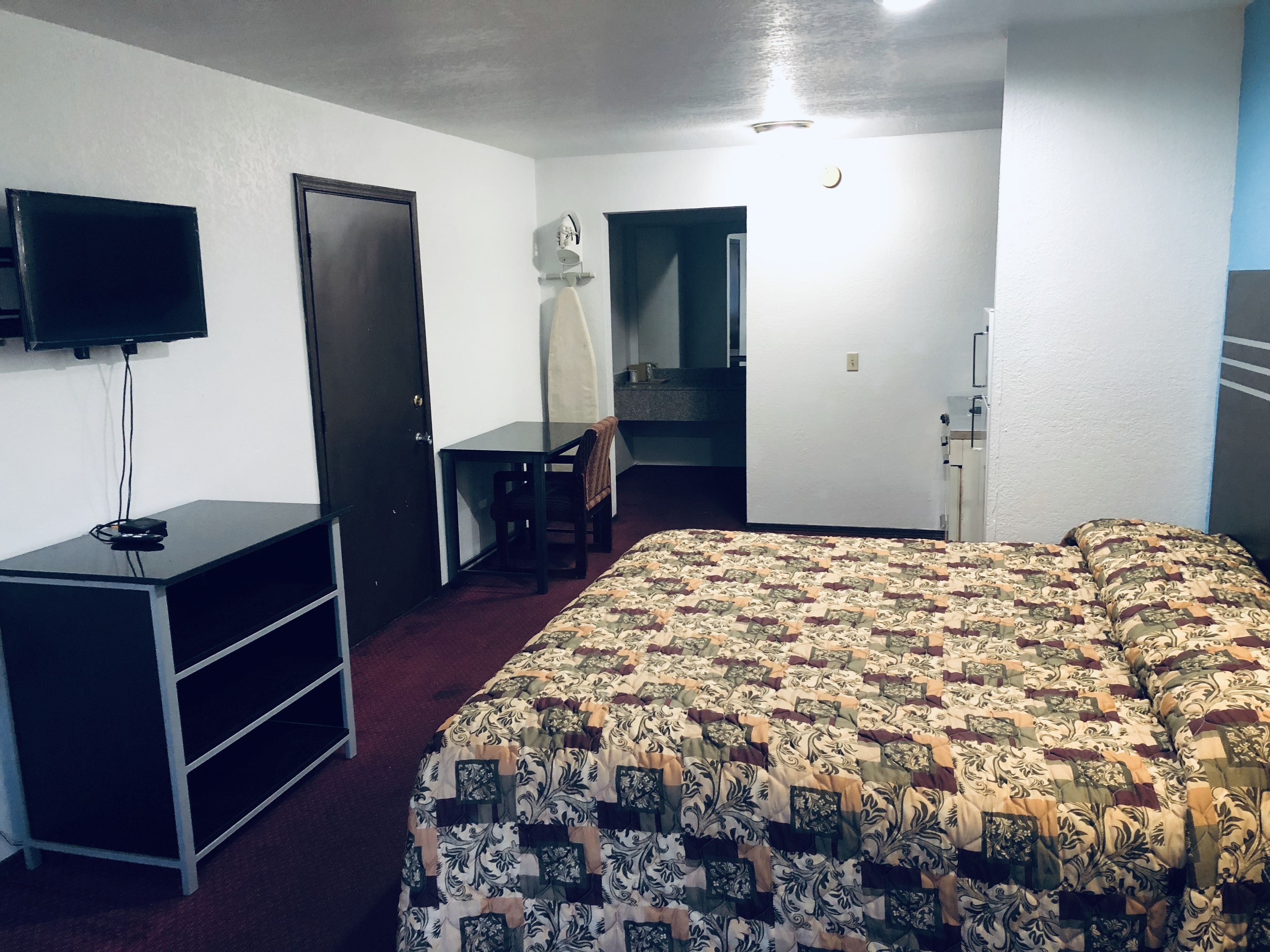 Une chambre d’hôtel équipée d’un lit, d’un bureau, d’une chaise, d’une télévision et d’un miroir.