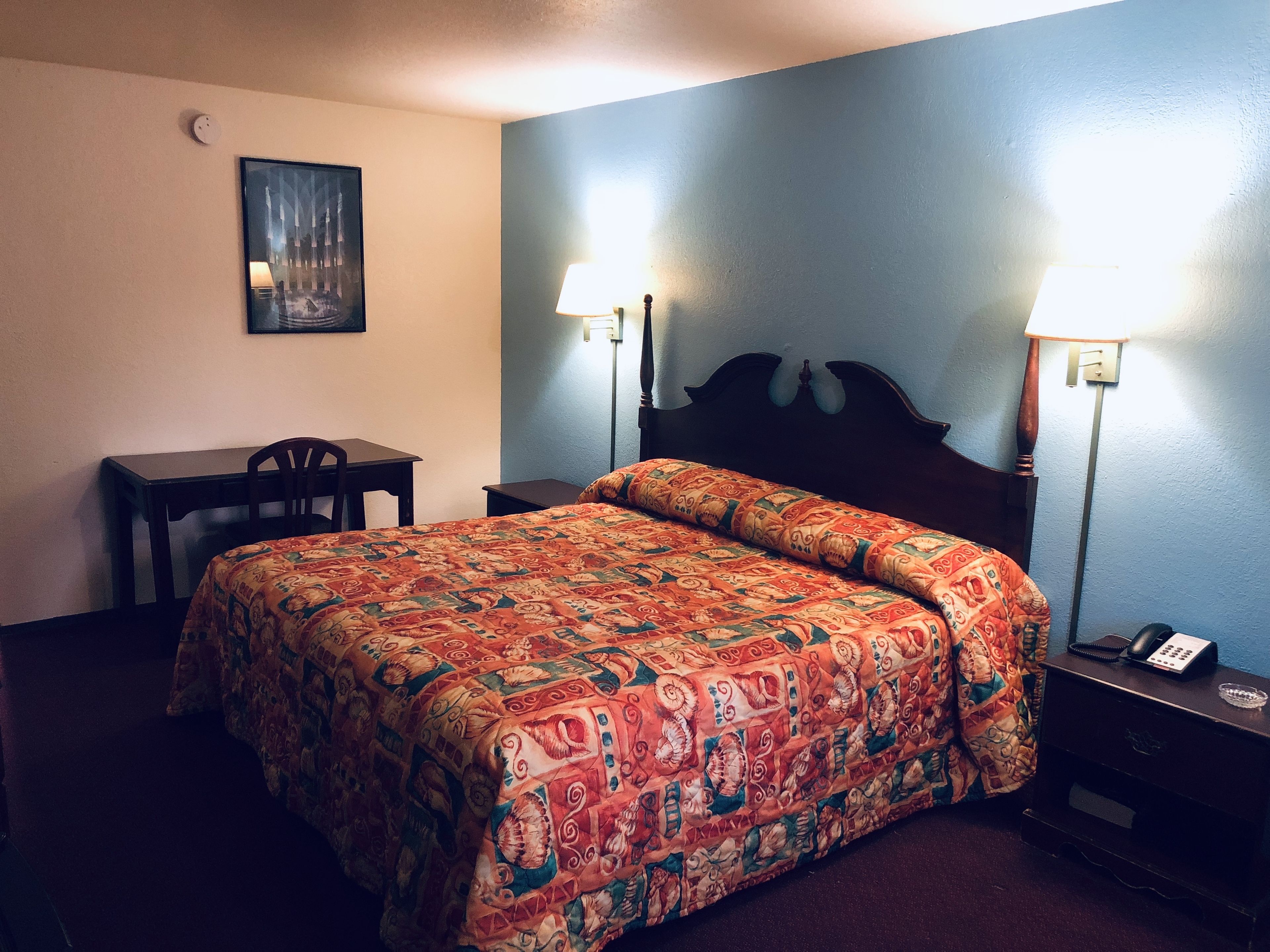 Una habitación de hotel con una cama, un escritorio y dos lámparas de noche.