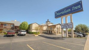 Un hôtel de la chaîne Meridian, reconnaissable à son grand panneau, son parking et son bâtiment doté d’un toit plat.