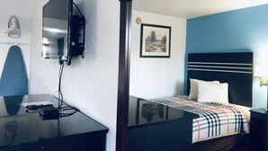 Une chambre à coucher comprenant un lit, une table de chevet, un miroir et un téléviseur fixé au mur.