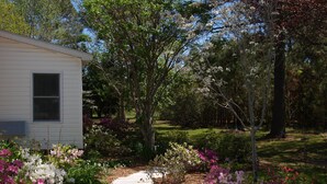 Un chemin qui mène à une maison blanche, entourée de jardins luxuriants et d’arbres.