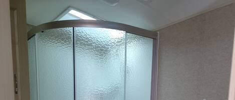 A compact bathroom with a glass shower enclosure, a toilet, and a sink with a countertop.