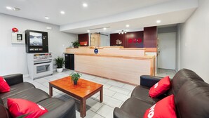 Un hall d’hôtel moderne comprenant un comptoir d’accueil, un espace salon et une kitchenette.