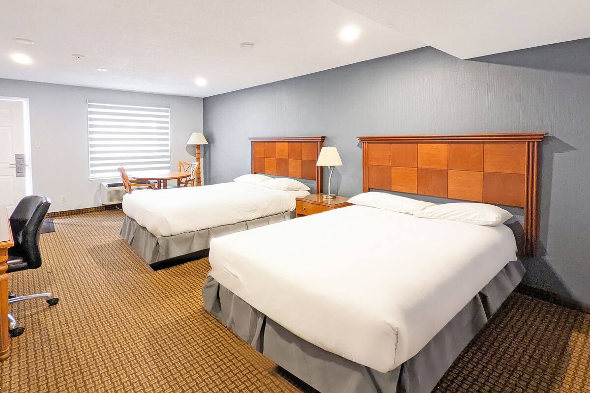 Ein Hotelzimmer mit zwei Betten, einem Schreibtisch und einem Sessel.