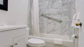 A bathroom with a toilet, bathtub, and shower area.
