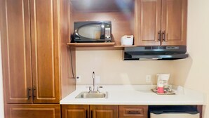 Une cuisine avec des meubles de rangement en bois, un four à micro-ondes, un évier et un réfrigérateur.