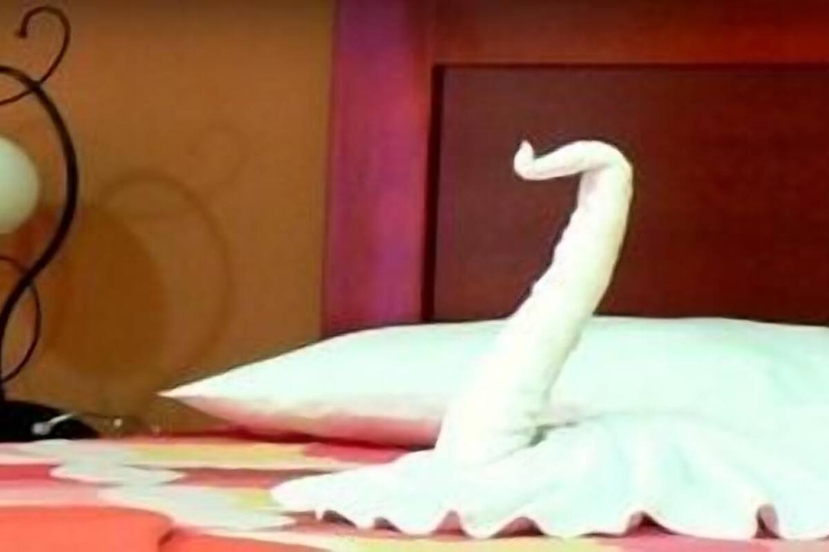 A bed with white pillows and a decorative swan.