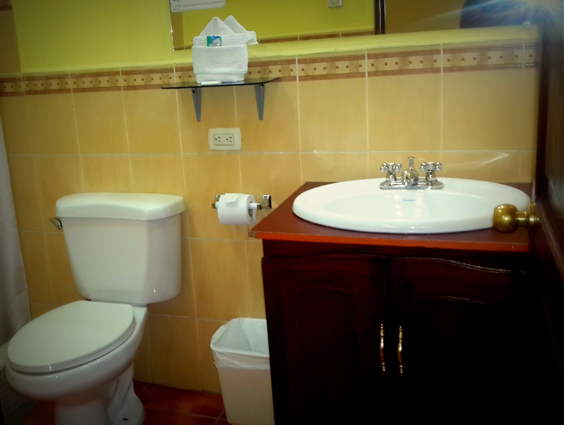 A bathroom with a toilet, sink, and trash bin.