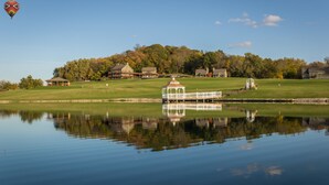 A tranquil lakeside scene with a gazebo and a hot air balloon in the sky. - Lefevre Inn and Resort (Galena)