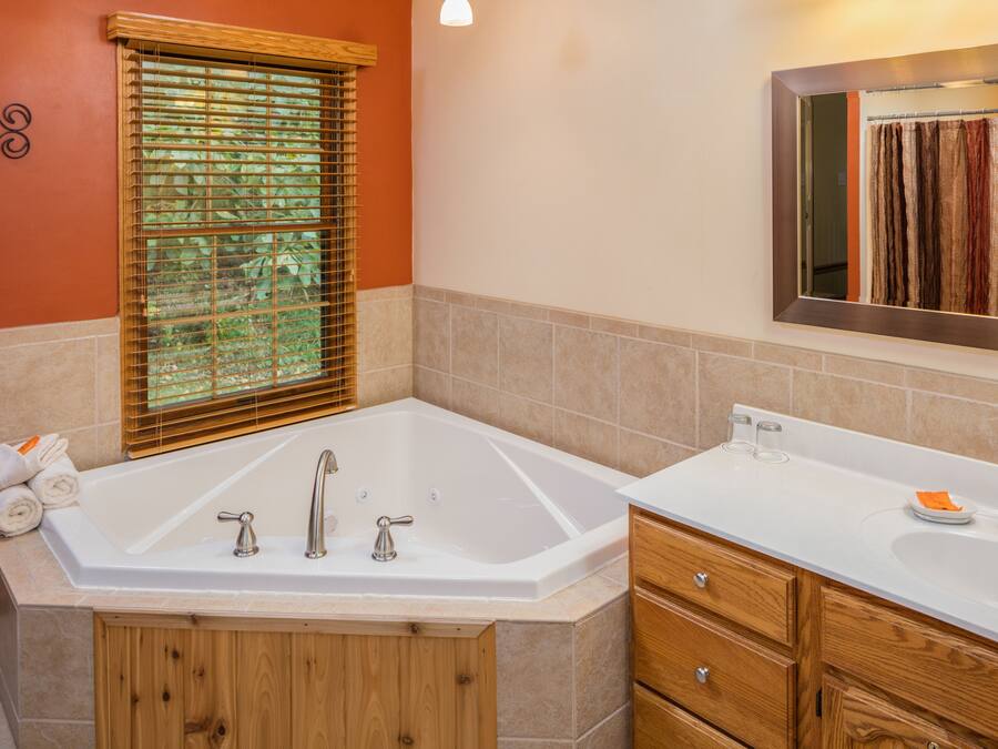 Une salle de bain avec une grande baignoire, des meubles en bois et un miroir au-dessus du lavabo.