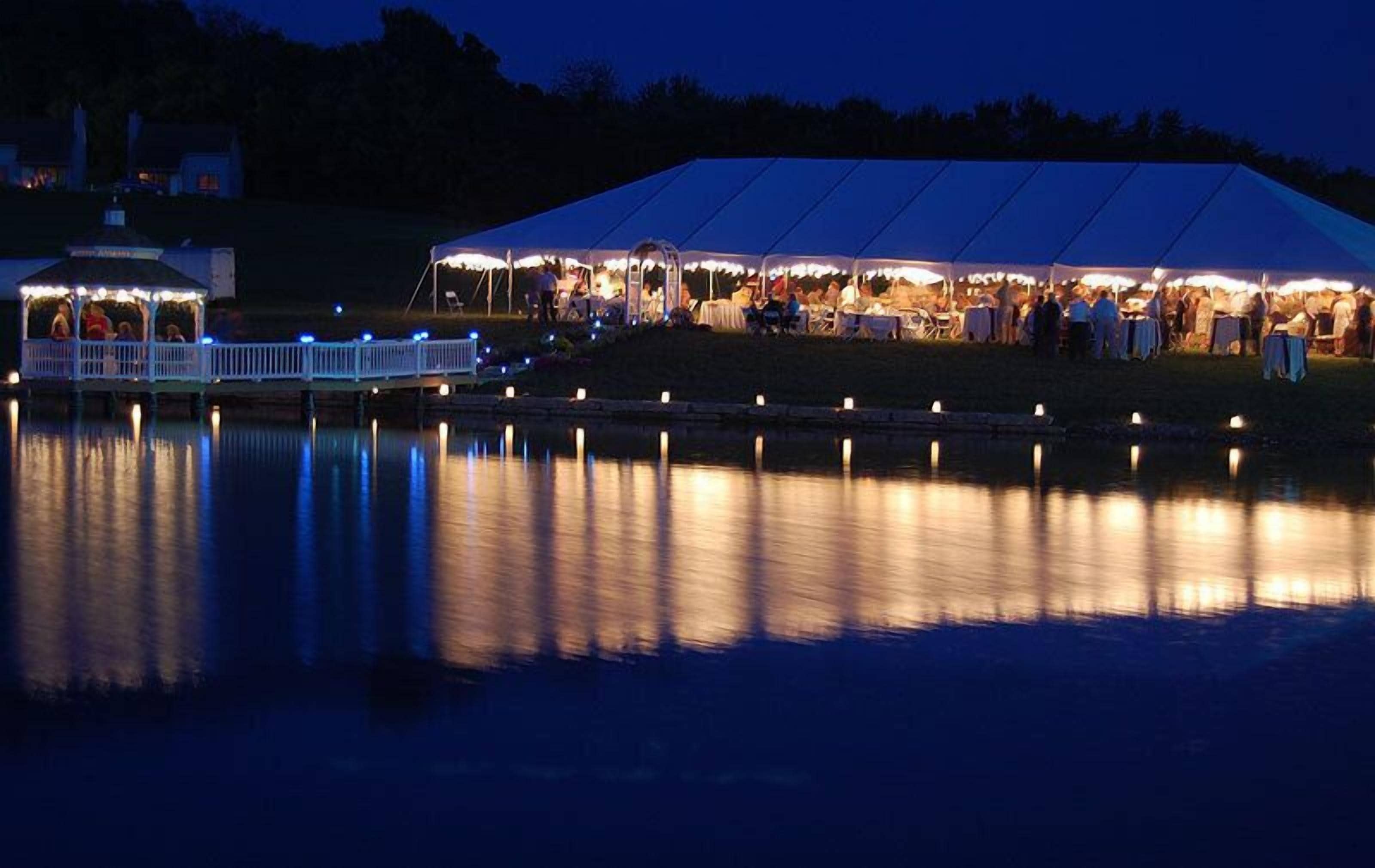 Un amplio espacio para eventos cubierto con carpas, con mesas y sillas dispuestas para una reunión al aire libre.