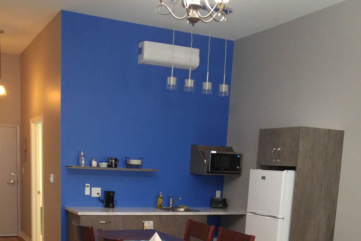 Eine kompakte Küche mit Mikrowelle, Kühlschrank und einer blauen Akzentwand.