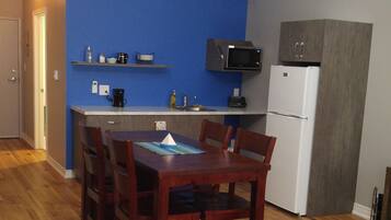 Una cocina compacta con microondas, refrigerador y una pared azul decorativa.