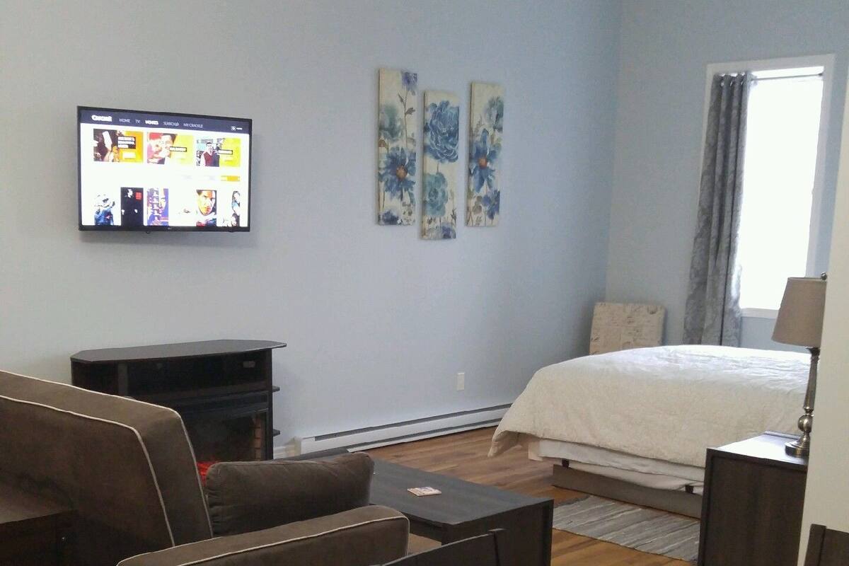 Ein Wohnzimmer mit Flachbildfernseher, einer Couch, einem Couchtisch und einem Bett.