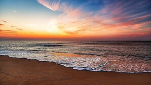Una playa con olas y un atardecer.