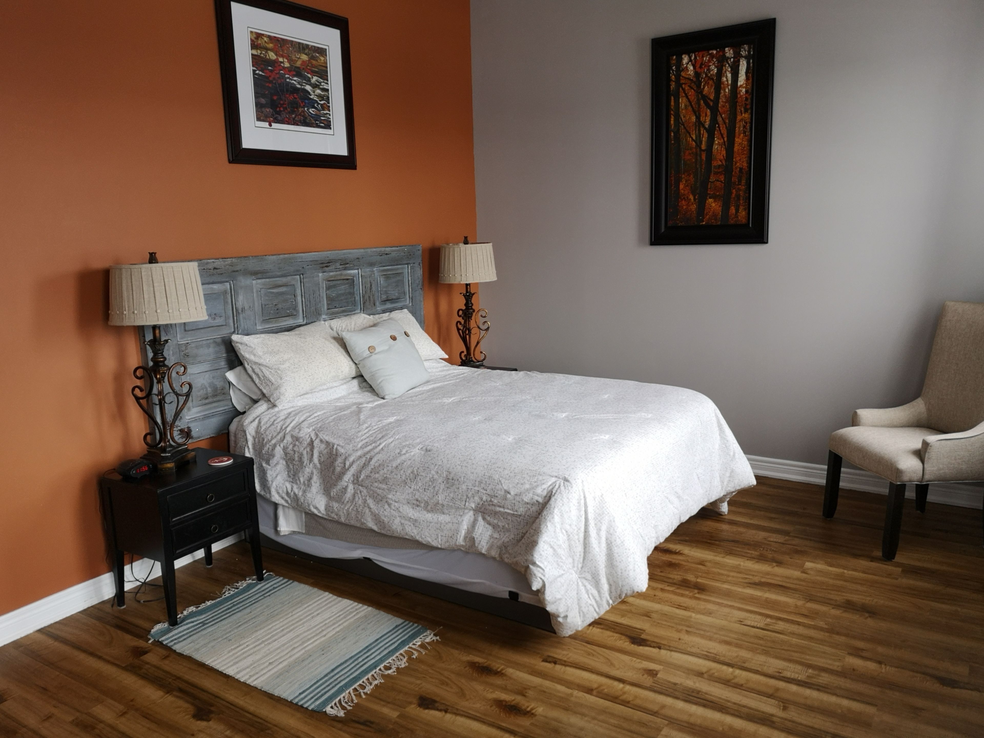 A bedroom with a bed, nightstands, a chair, and artwork on the walls.