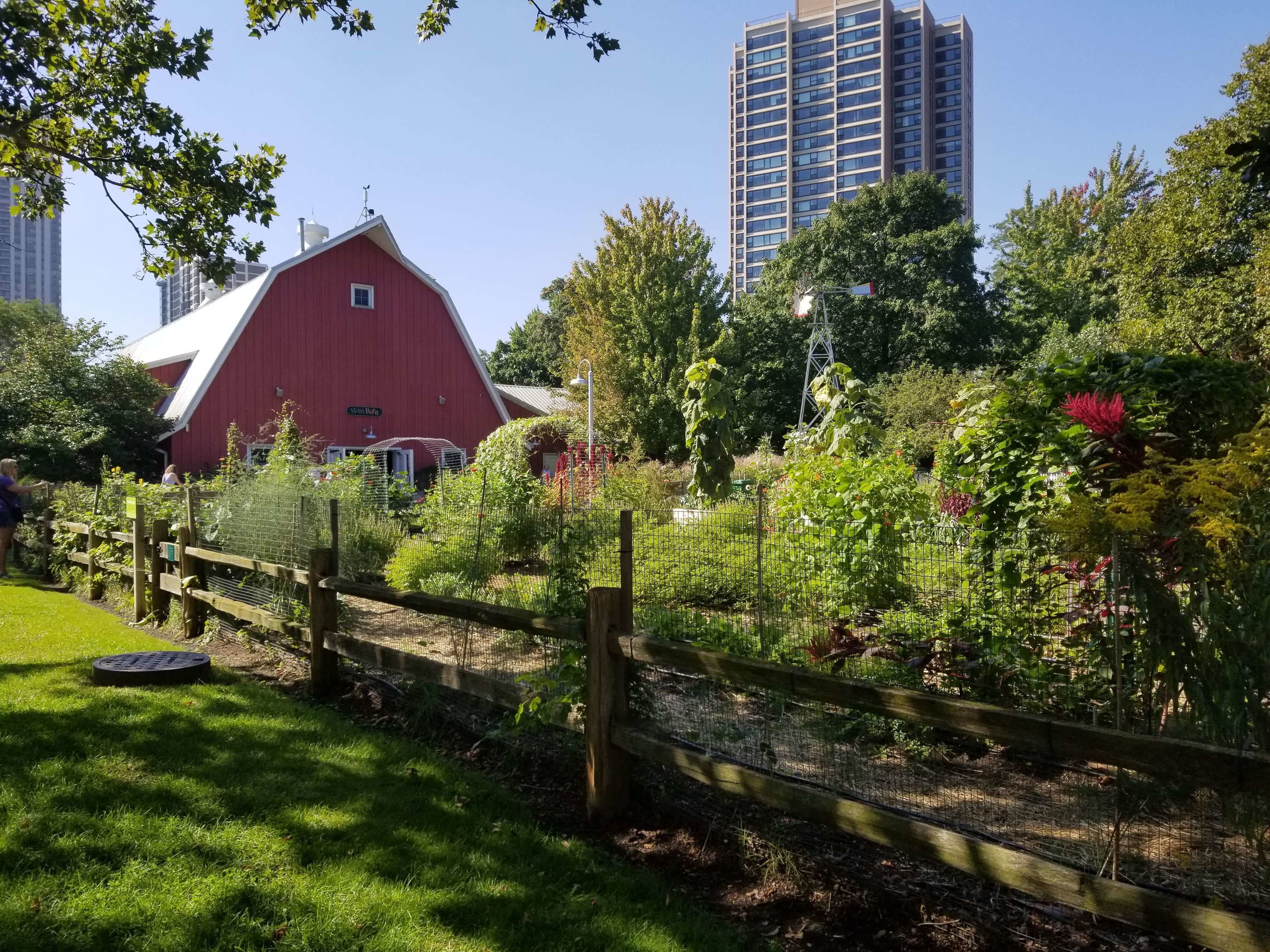 A red barn with a white roof, surrounded by lush greenery and a wooden fence.