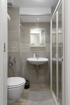 A modern bathroom with a white sink, a toilet, and a shower area. - B&B Maison Du La Rua (Naples)
