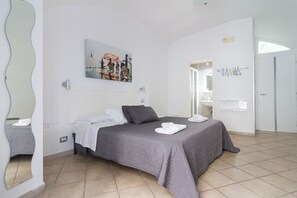 A bedroom with a bed, a painting, a bathroom with a sink, and a mirror. - B&B Maison Du La Rua (Naples)