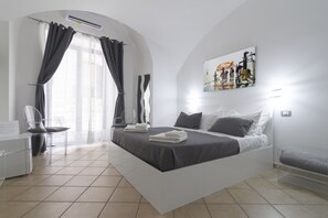 A modern hotel room with a large bed, a desk, and a chair. - B&B Maison Du La Rua (Naples)