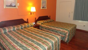 A hotel room with two beds, a nightstand, a lamp, and two framed pictures on the wall. - Sunset Motel (Taft)