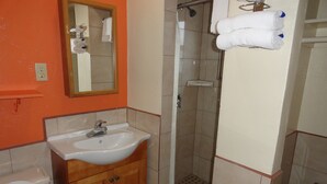 A bathroom with a sink, mirror, shower, and toilet. - Sunset Motel (Taft)