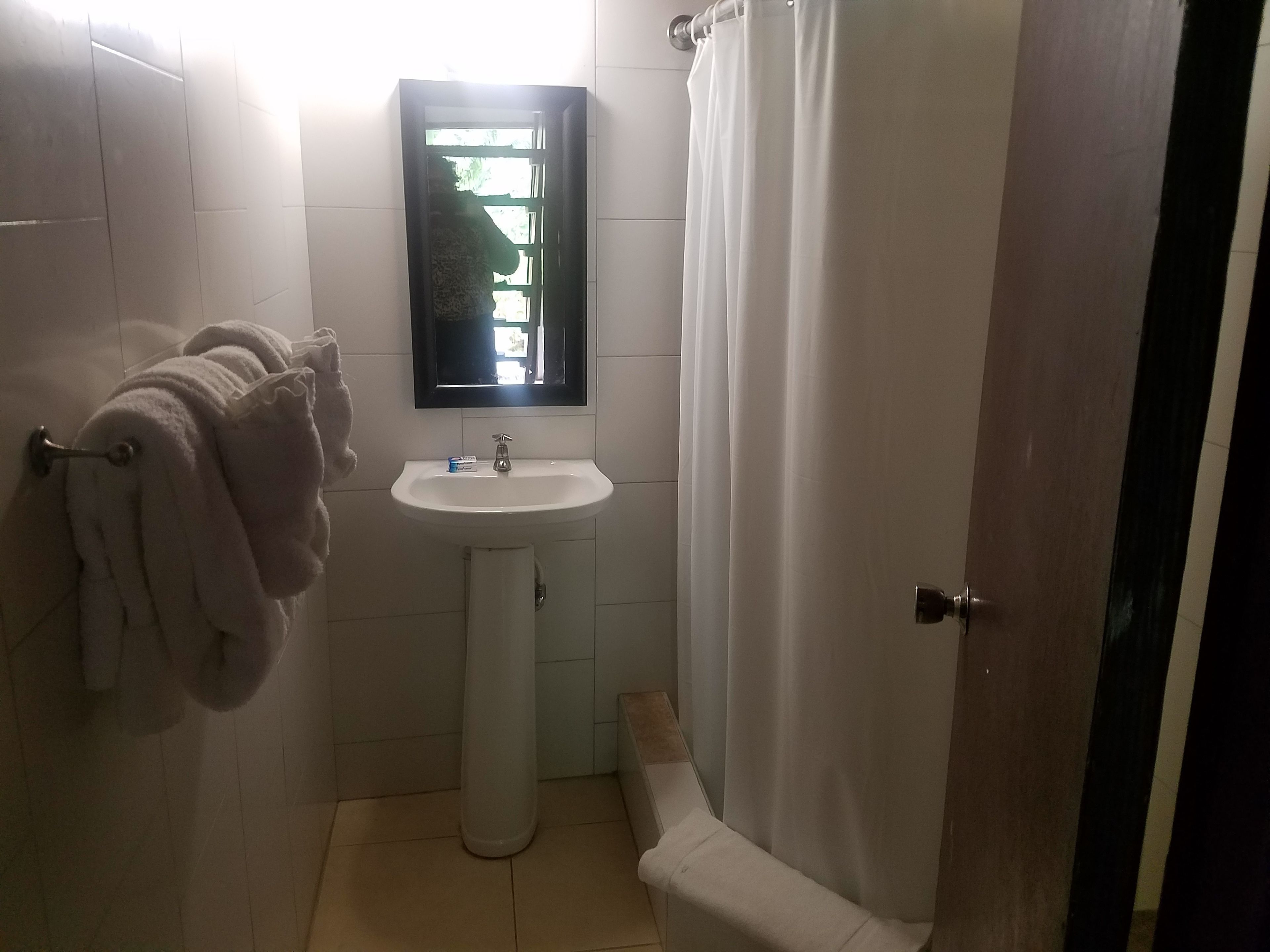 A bathroom with a white sink, a mirror, and a towel rack with towels.