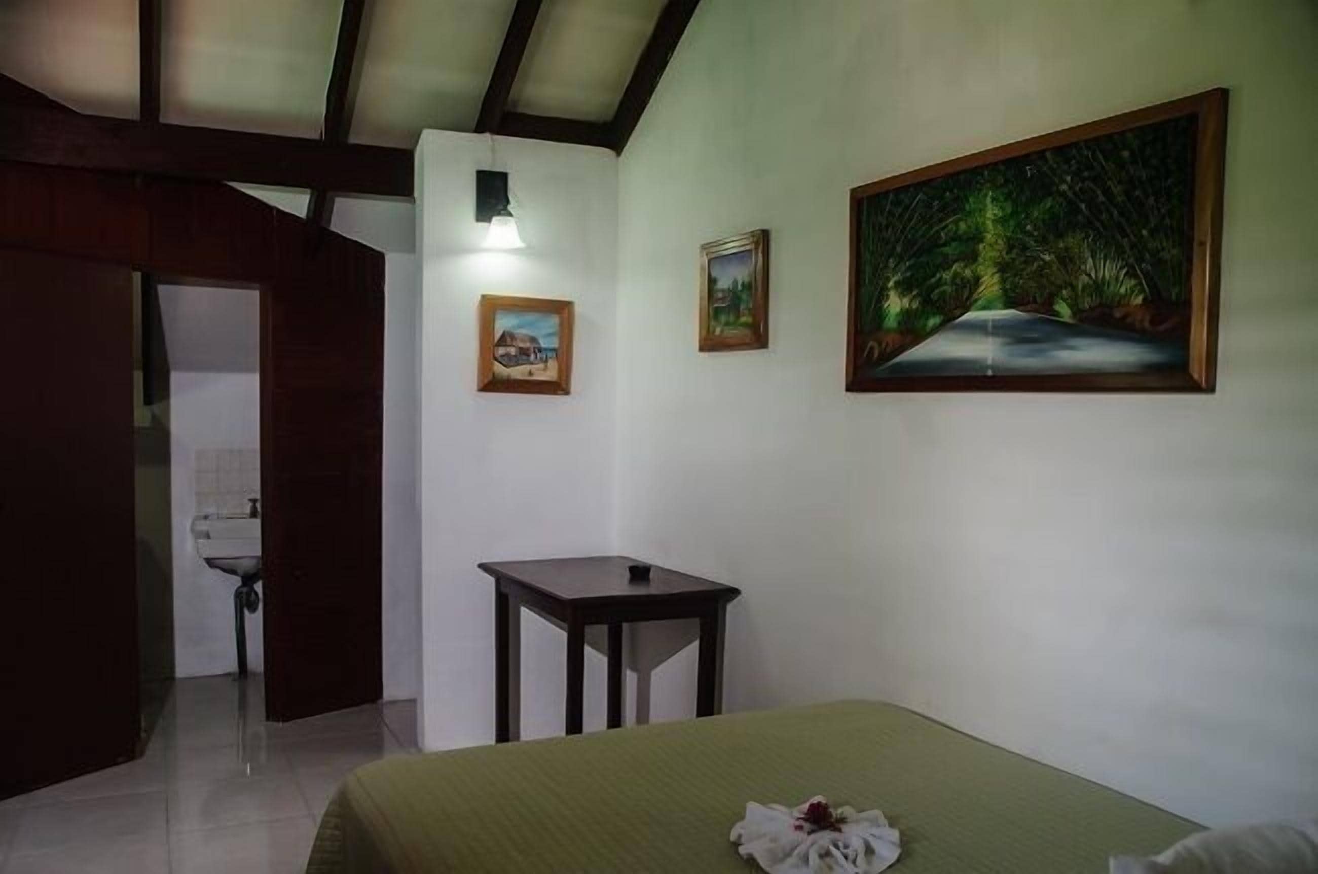 Une pièce comprenant un lit, une petite table et deux tableaux encadrés accrochés au mur.
