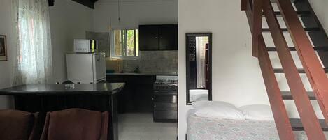 A compact living space with a kitchenette, a dining area with chairs, a bed, and a staircase.