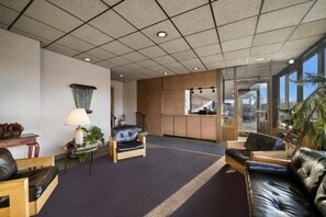 A lobby with a reception desk, seating area, and large windows.
