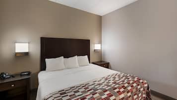 Ein Hotelzimmer mit einem großen Bett, zwei Nachttischen, einem Telefon und einer Lampe auf jeder Seite des Bettes.