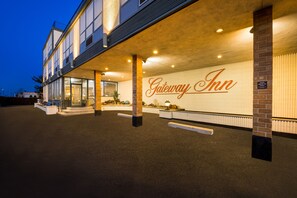 The exterior of Gateway Inn with a prominent entrance, a reception desk, and a sign indicating a parking area. - Gateway Inn (Merrick)