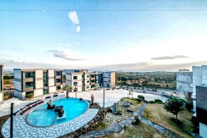 Un edificio moderno con piscina, mobiliario exterior y vistas al paisaje circundante.