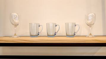 A wooden shelf with four clear glass mugs and two wine glasses.