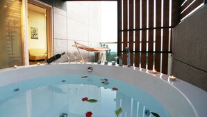 A hot tub with candles and flowers, a hammock, and a view of a building. - Donnaekohill Resort (Seogwipo)