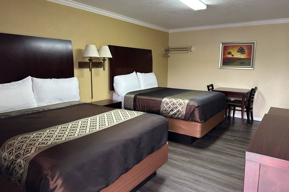 Une chambre d’hôtel avec deux lits, un bureau et une chaise.